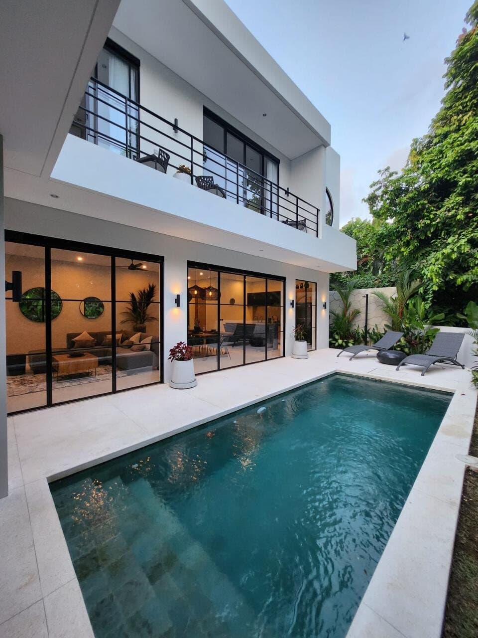 The pool running along the front of the house, upper balcony above